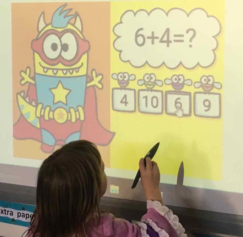 A child interacting at a smart board with a BOOM Learning resource in play